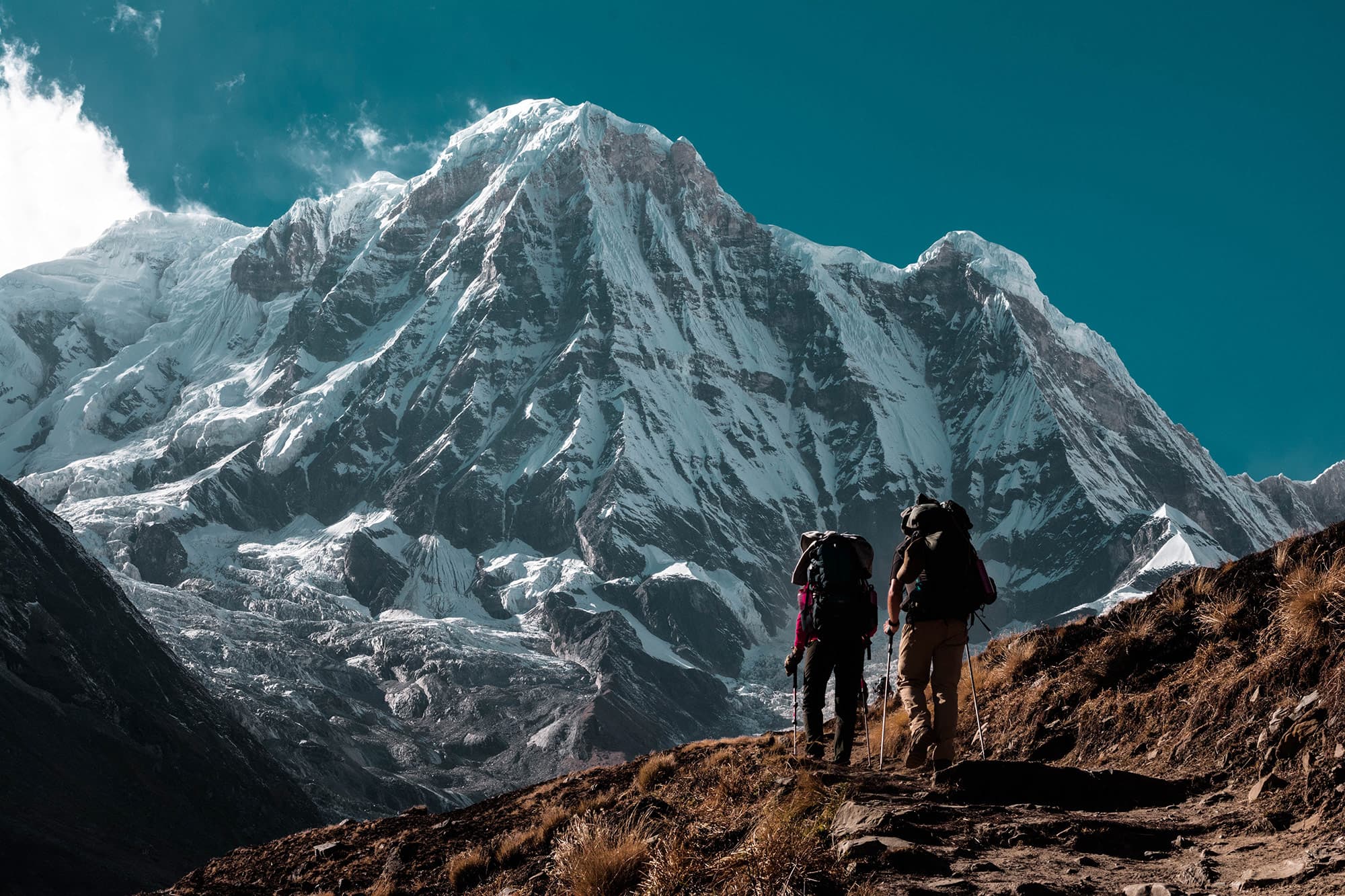 Dos montañeros subiendo hacia una cumbre nevada